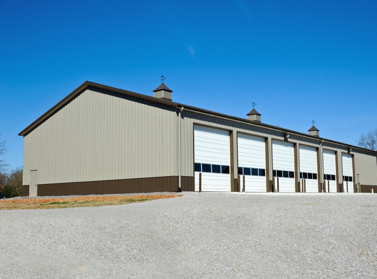 Tan steel building with a row of overhead doors